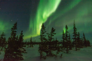 Powerful aurora borealis and northern lights fill the sky behind