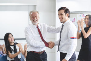 Young businessman promoted. Boss shaking hands with employee cel